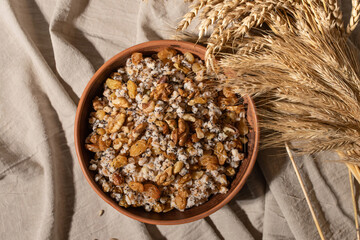 Kutia, traditional Ukrainian Christmas dish. Wheat cereal with poppy seeds, raisins and nuts on clay brown plate, on neutral beige linen tablecloth background. Food for Christmas Eve in Ukraine