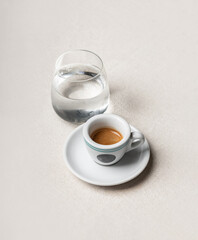 Cup of Espresso and Glass of Water on Light Table with Copy Space