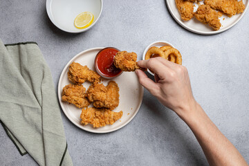 Hand Holding Crispy Chicken Over Plate