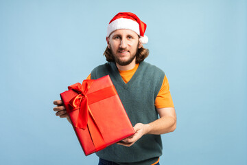 Man in Santa hat giving a red Christmas present with a happy smile