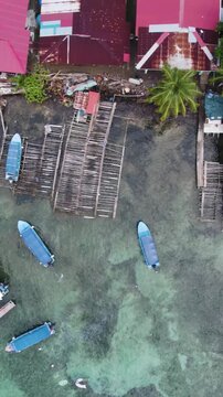 Vertical aerial birds-eye view of colorful boats docked along the shoreline of Bastimentos Island in Bocas del Toro District, Panama.
