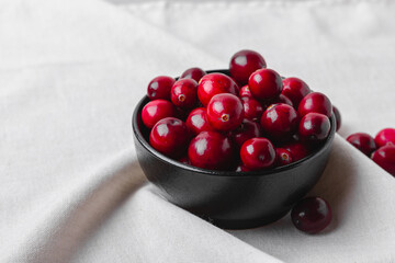 Black bowl of cranberries resting in soft fabric folds
