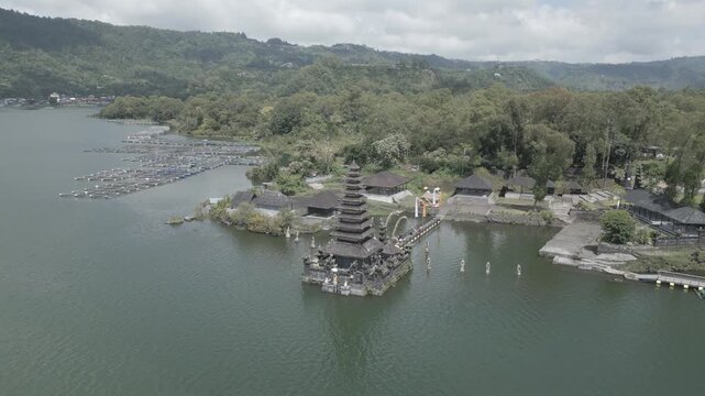 Aerial drone view of Pura Ulun Danu Beratan water temple on Lake Beratan in Bedugul Bali Indonesia. Sacred shrine rises from calm lake with misty hills and serene mountain landscape.