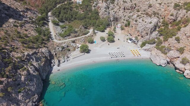 Drone shot of Achata Beach in Karpathos, rising in height and tilting up to reveal the landscape