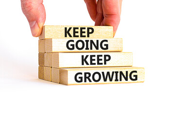 Keep going and growing symbol. Concept words phrase Keep going keep growing on beautiful wooden blocks. Beautiful white background. Businessman's hand. Business Keep going growing concept. Copy space.