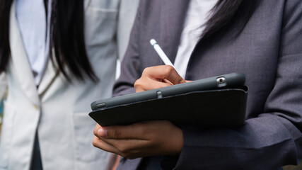 Business professional using a digital tablet and stylus for field data collection, analysis, and documentation in a modern outdoor work environment.