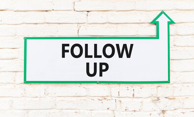 Obraz premium Follow up symbol. Concept word Follow up on beautiful white sign on white brick wall. Beautiful white brick wall background. Business follow up concept. Copy space.
