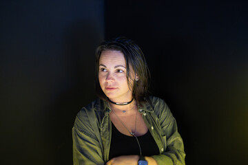 Dark haired woman in shirt and top in dark room, emotional portrait concept