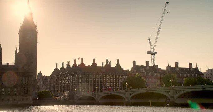 Red buses, traffic and people on Westminster Bridge at dusk over the River Thames next to Big Ben and The Houses of Parliament, London, England
