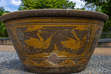 Ceramic decorative vintage flower pot with a pattern of dancing storks in a park in Bangkok, Thailand 