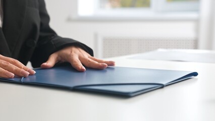 Businessperson Hand on Blue Document Folder in Office