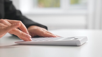 Close up of Hand Using a White Calculator on Desk