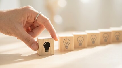 A hand pushes a wooden block with a keyhole design in a row of similar blocks on a light colored surface in a blurry setting