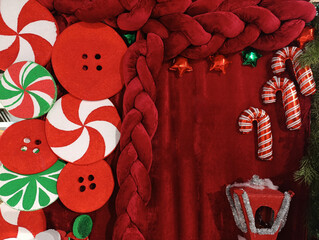 Christmas decorations on a red velvet background, large candy hooks, and lollipops. Hall decorations. A place for Christmas family photos. Merry Christmas, Happy New Year.