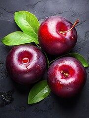 Three Red Plums with Leaves on Dark Background