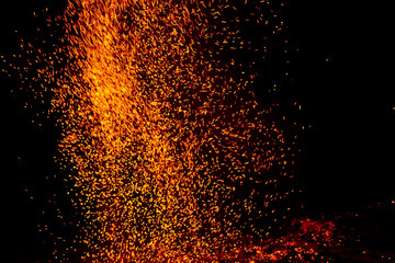 Towering golden plume of embers shooting upward into the night, dense storm of glowing sparks rising from a hidden campfire like a fiery waterfall frozen in midair   © Nature