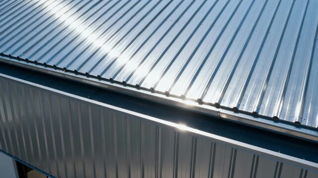 Closeup medium shot of galvanized metal roofing panels with a shiny silver finish reflecting sunlight to reduce heat absorption in modern building designs