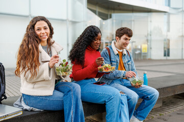Multiethnic friends enjoying a salad meal together outdoors at university
