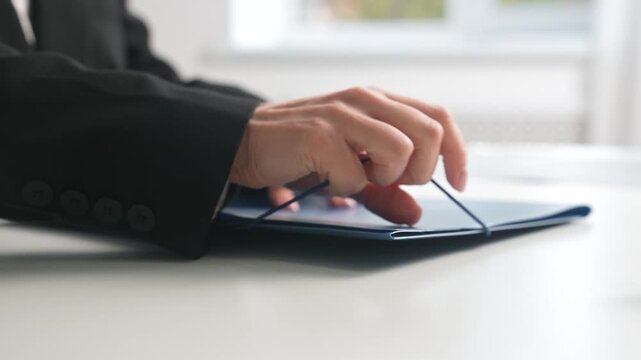 Businessperson Hand on Blue Document Folder in Office