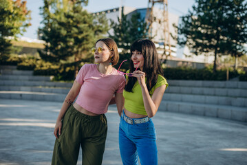 Stylish girlfriends rests after quad skating in urban park
