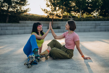 
Cheerful women give high five after a great roller skating in park