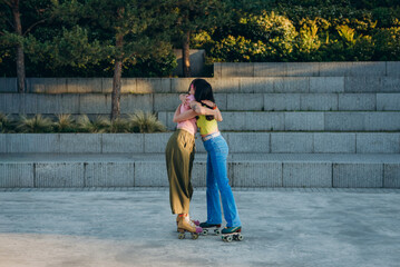 
Female friends express joy of meeting and hug in roller skate park

