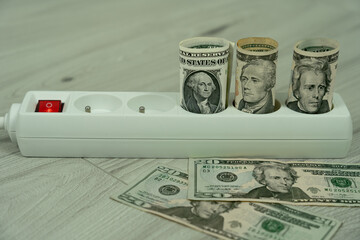 rolled us dollar banknotes in power strip illustrating high electricity prices in the amer region and the rising cost of household energy during the utility crisis