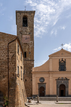 Italy - Bagnoregio - Civita di Bagnoregio - Church of San Donato and Romanesque bell tower rising over main square under bright sky, historic stone facades