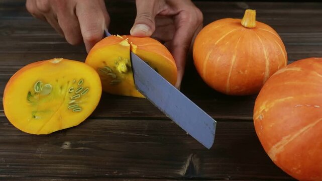 Close up woman hand cutting pumpkin on the table.