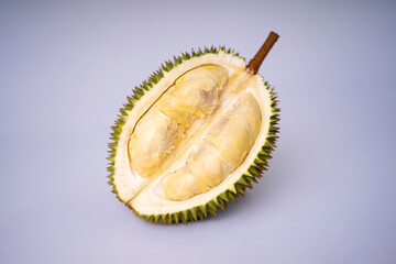 Fototapeta premium Premium shot of a halved durian fruit, revealing rich creamy yellow pulp and a sharp spiky husk. Fresh tropical exotic fruit isolated on a plain white background