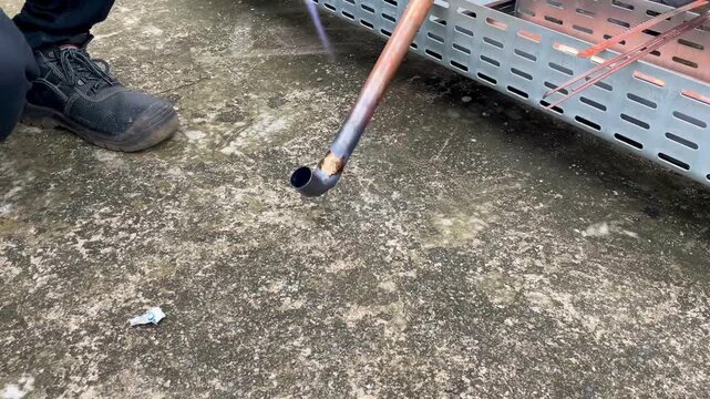 Seorang pekerja mengelas pipa logam di lokasi konstruksi untuk sebuah toko baru.