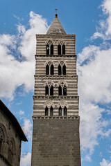 Fototapeta premium Italy - Viterbo - Cattedrale di San Lorenzo - Full striped campanile with trilobed arches and pointed spire under blue sky
