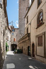 Fototapeta premium Italy - Viterbo - San Pellegrino - Narrow street with historic palazzo, arches and tower in background