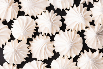 Fresh homemade meringue cookies over black background