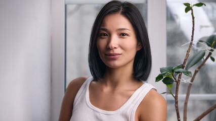 Natural female portrait near window with soft daylight. Concept of everyday beauty, real skin texture, casual lifestyle portrait, personal branding, social media content and modern advertising.