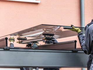 Workers install patio roofing with steel and glass
