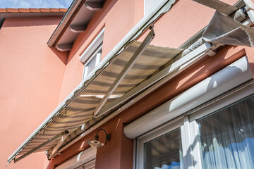 Dirty and broken retractable awning installed on family house