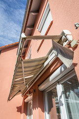 Dirty and broken retractable awning installed on family house