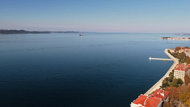 Aerial drone view of Zadar's red roofed buildings along the bright blue Adriatic Sea