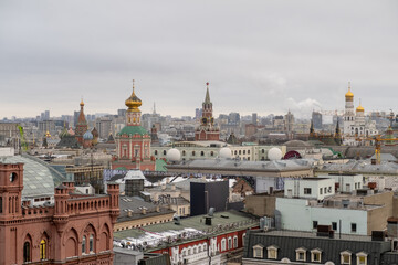 Fototapeta premium Urban Skyline View of Historic Buildings in Moscow With Colorful Domes and Modern Cityscape Under Overcast Sky