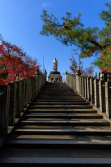 青空の下まっすぐ伸びる石段と観音像（寂光院・犬山）

