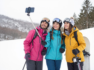 Friends take selfie on snowy mountain slope during winter vacation