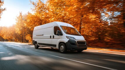 Fototapeta premium White delivery van driving fast on a road through a forest with autumn orange leaves