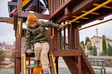 Child climbs down playground structure in local park during afternoon playtime with friends