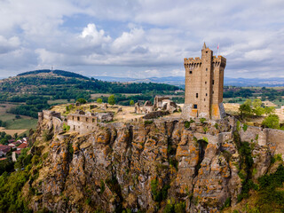 Obraz premium Medium-angle aerial view of Forteresse de Polignac with its central Donjon, showcasing the hilltop fortress, stone walls, and surrounding green landscape.