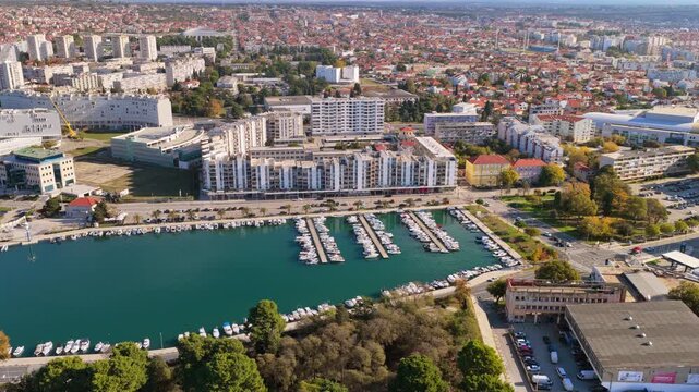 Aerial drone view of Zadar's marina filled with yachts and small boats, surrounded by modern residential and commercial buildings