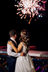 A newlywed couple watches a wedding fireworks display against