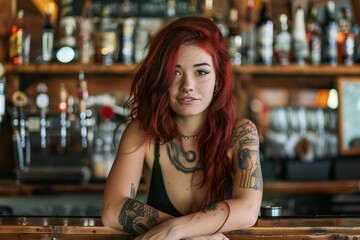 Young bartender with tattoos and red hair leaning on the counter in a bar