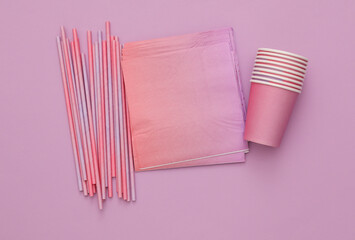 Set of disposable tableware for birthday party on purple background. Top view