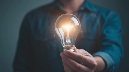 Person holding illuminated light bulb symbolizes idea innovation creativity - Powered by Adobe